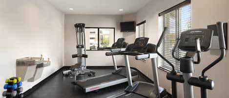A gym with treadmills, weight machines, and dumbbells.