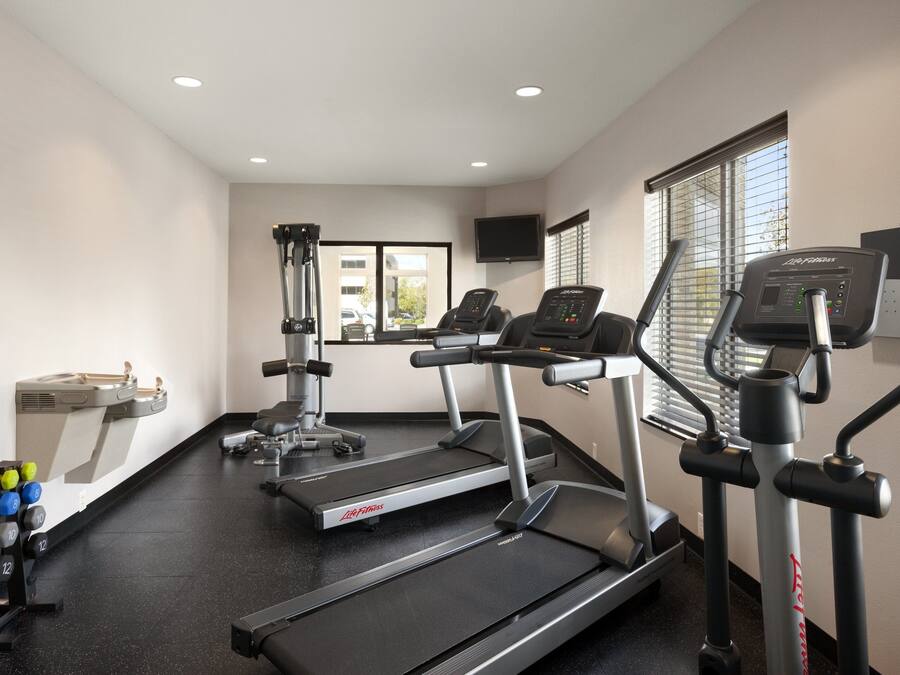 Un gimnasio con cintas de correr, máquinas de pesas y mancuernas.