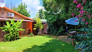 A well-maintained garden with a lawn, a wooden house, and a satellite dish. - Premiere Guest House (Bloemfontein)