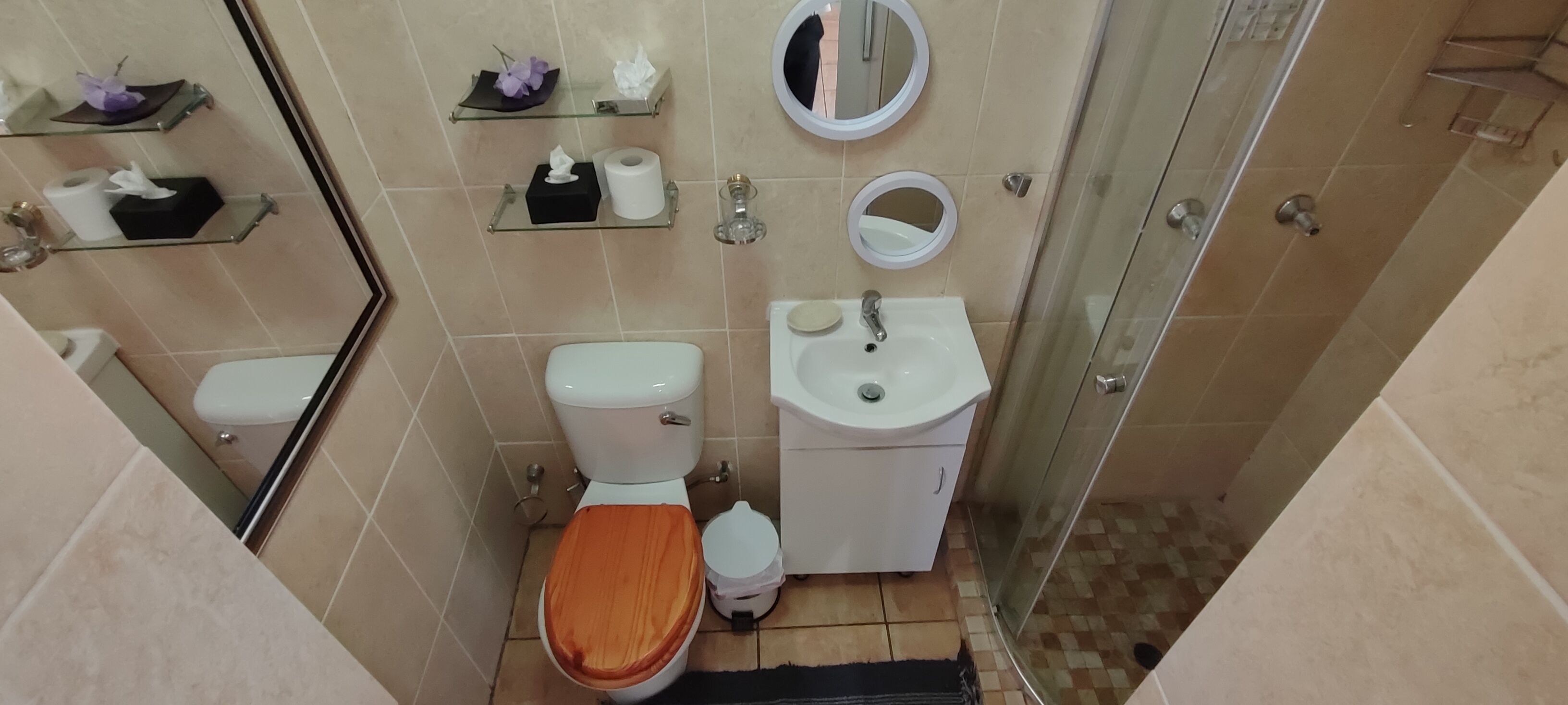 A compact bathroom with a toilet, sink, and a glass shower enclosure.