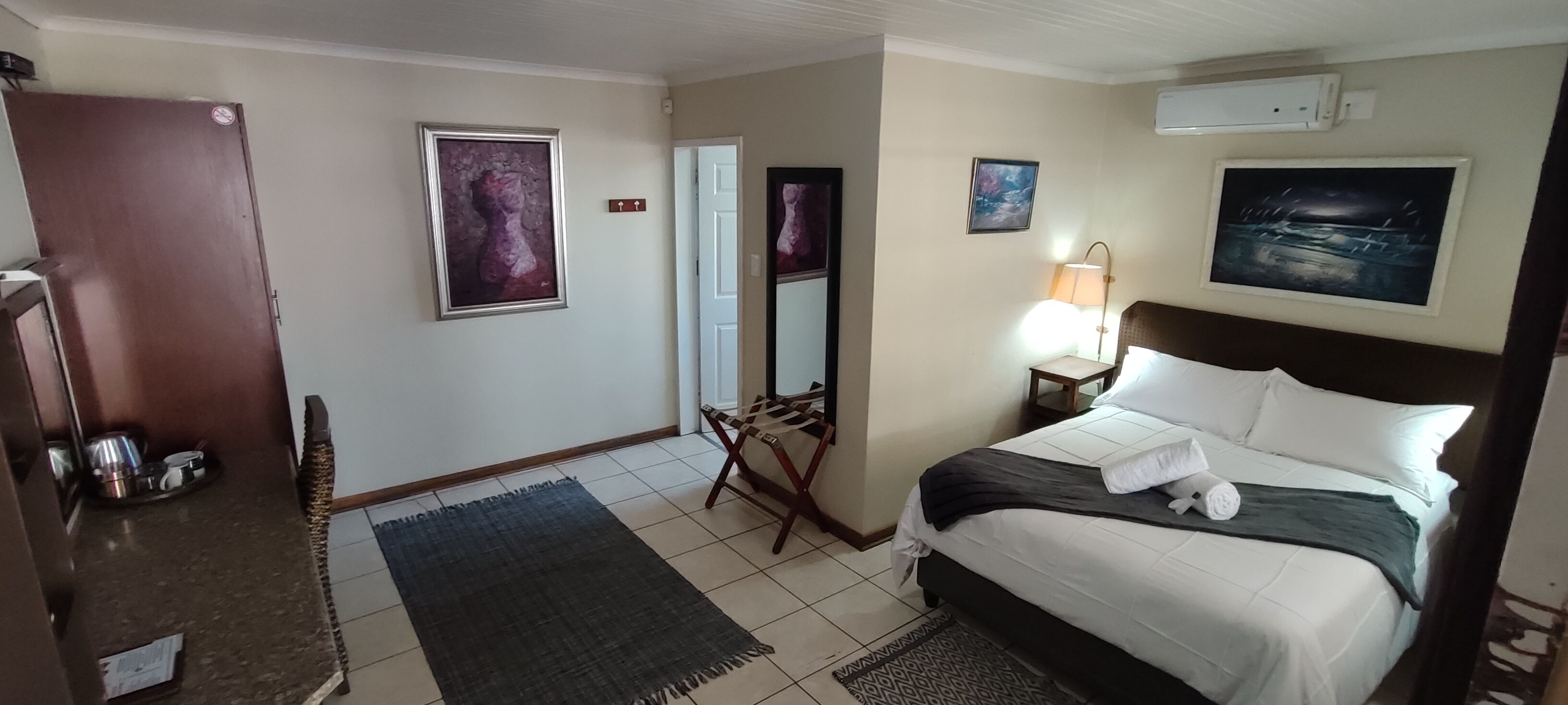 Ein Hotelzimmer mit Bett, Schreibtisch, Stuhl, Spiegel und Tür.
