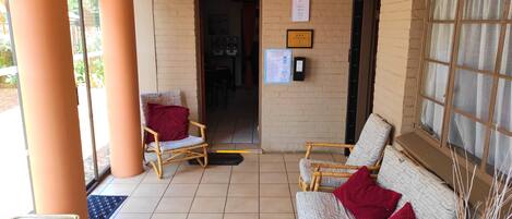 A breakfast area with wicker chairs, a red pillow, and a certificate on the wall.