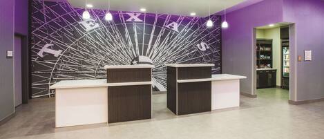 A reception area with a modern design, featuring a reception desk and a wall with a geometric pattern.