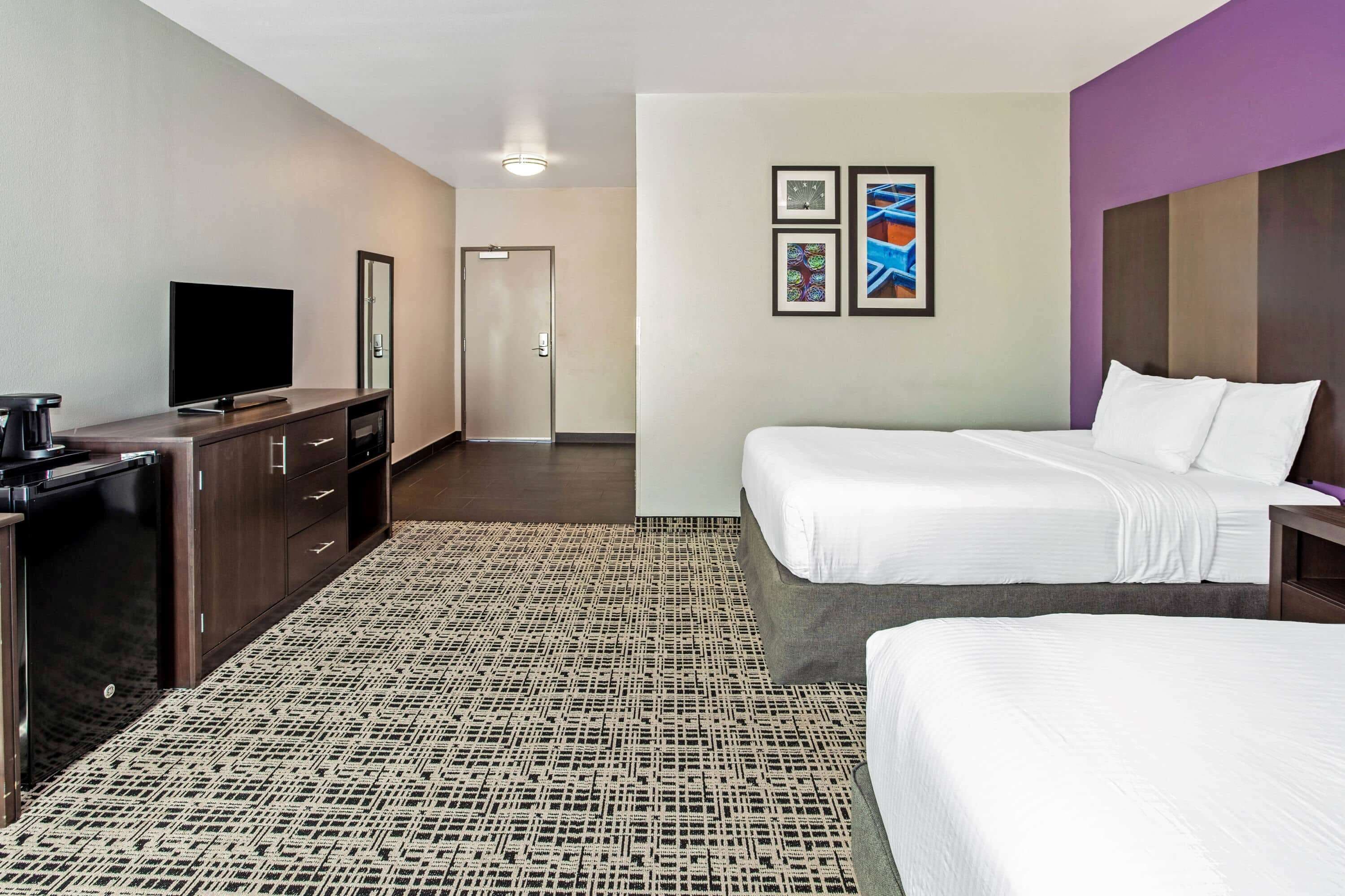 A hotel room with a bed, a TV, a desk, and a wardrobe.