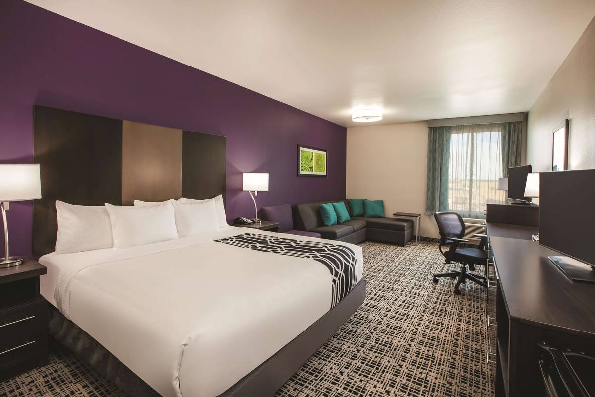 Een hotelkamer met een groot bed, een bank, een bureau en een televisie.