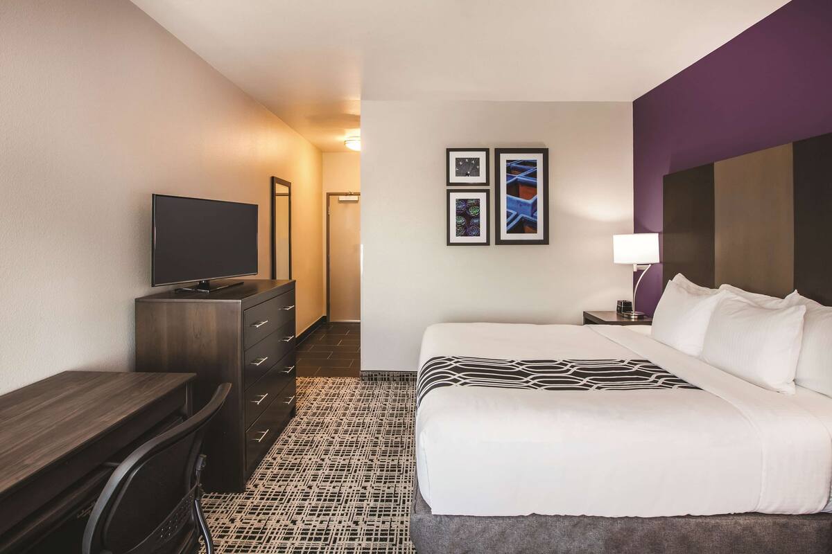 Een hotelkamer met een bed, een bureau, een televisie en een dressoir.