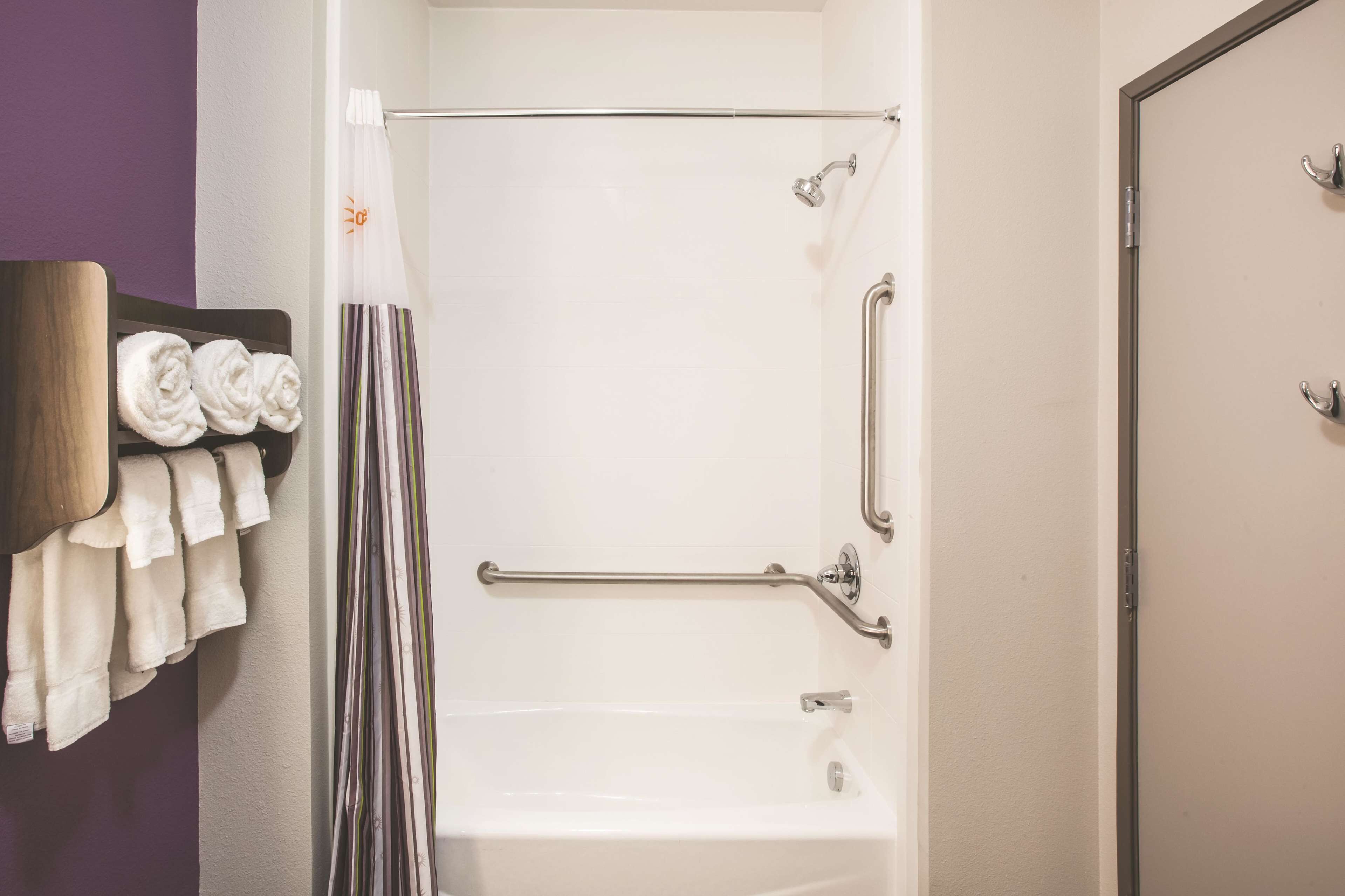 A bathroom with a white bathtub, a shower with a glass door, and a towel rack with folded towels.