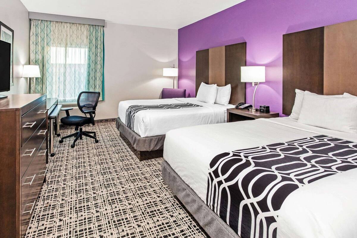Een hotelkamer met twee bedden, een bureau, een stoel en een televisie.