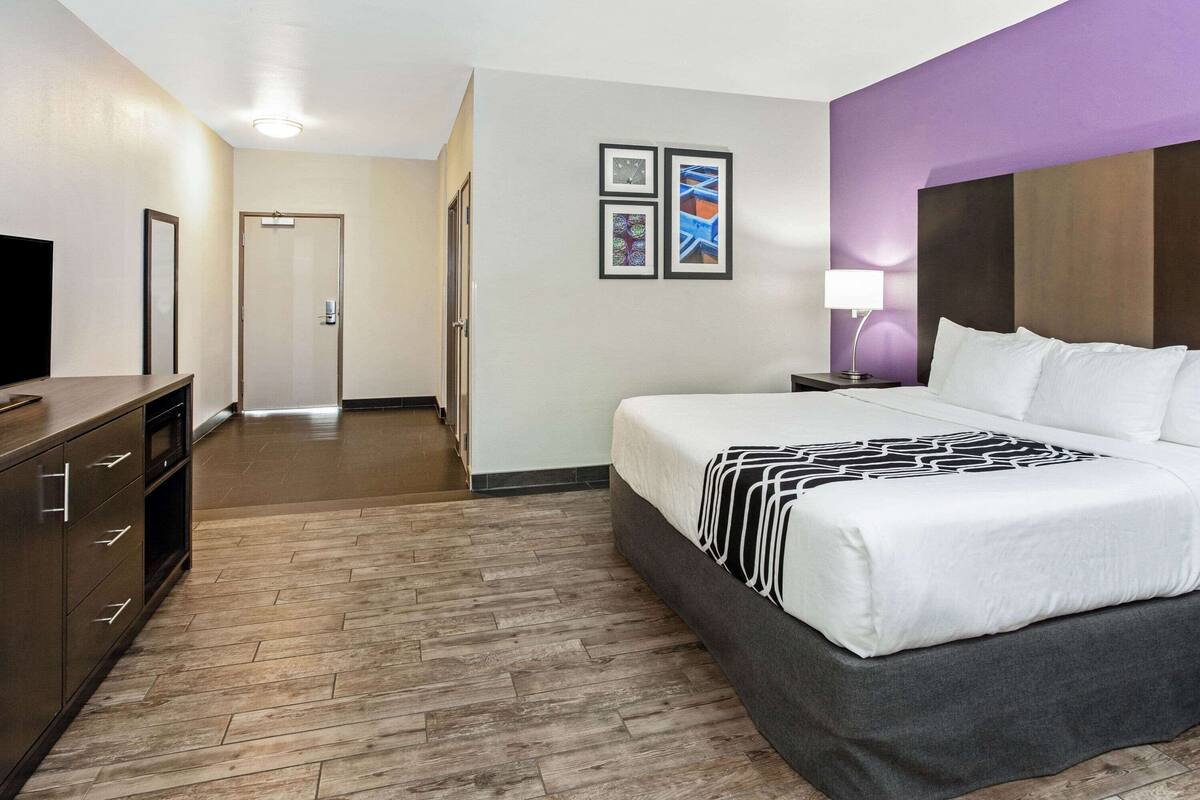 Een hotelkamer met een bed, een televisie, een bureau en een deur.
