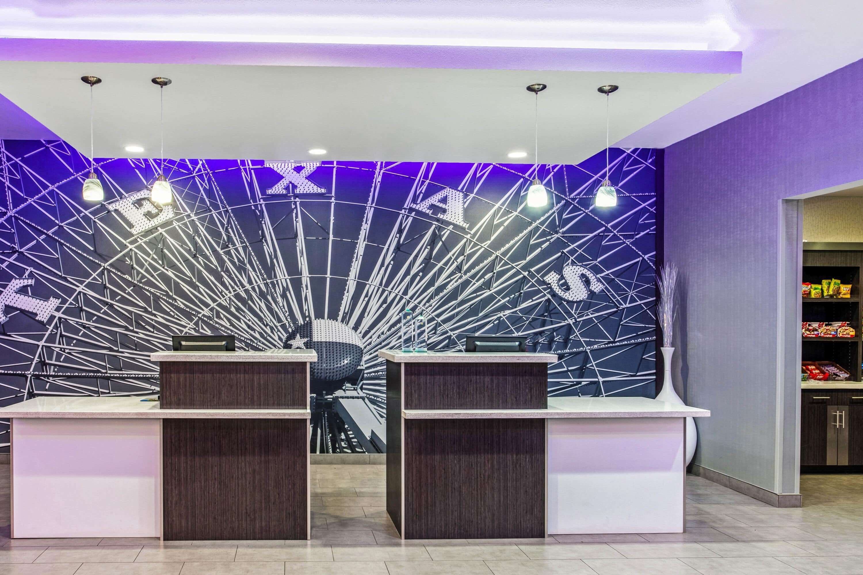 A reception area with two desks, a modern ceiling design, and a purple accent wall.