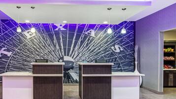 A reception area with two desks, a modern ceiling design, and a purple accent wall.