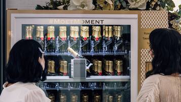 A display of champagne bottles with a sign reading 'DRINKS' and a hashtag '#MOETMOMENT'.