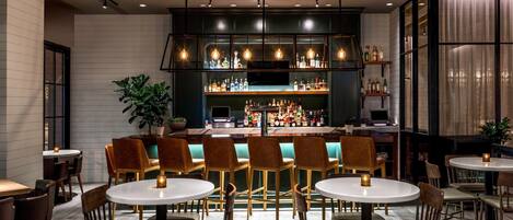 Un espace bar offrant différentes options de sièges, un comptoir bien garni de diverses bouteilles et un décor intérieur moderne.