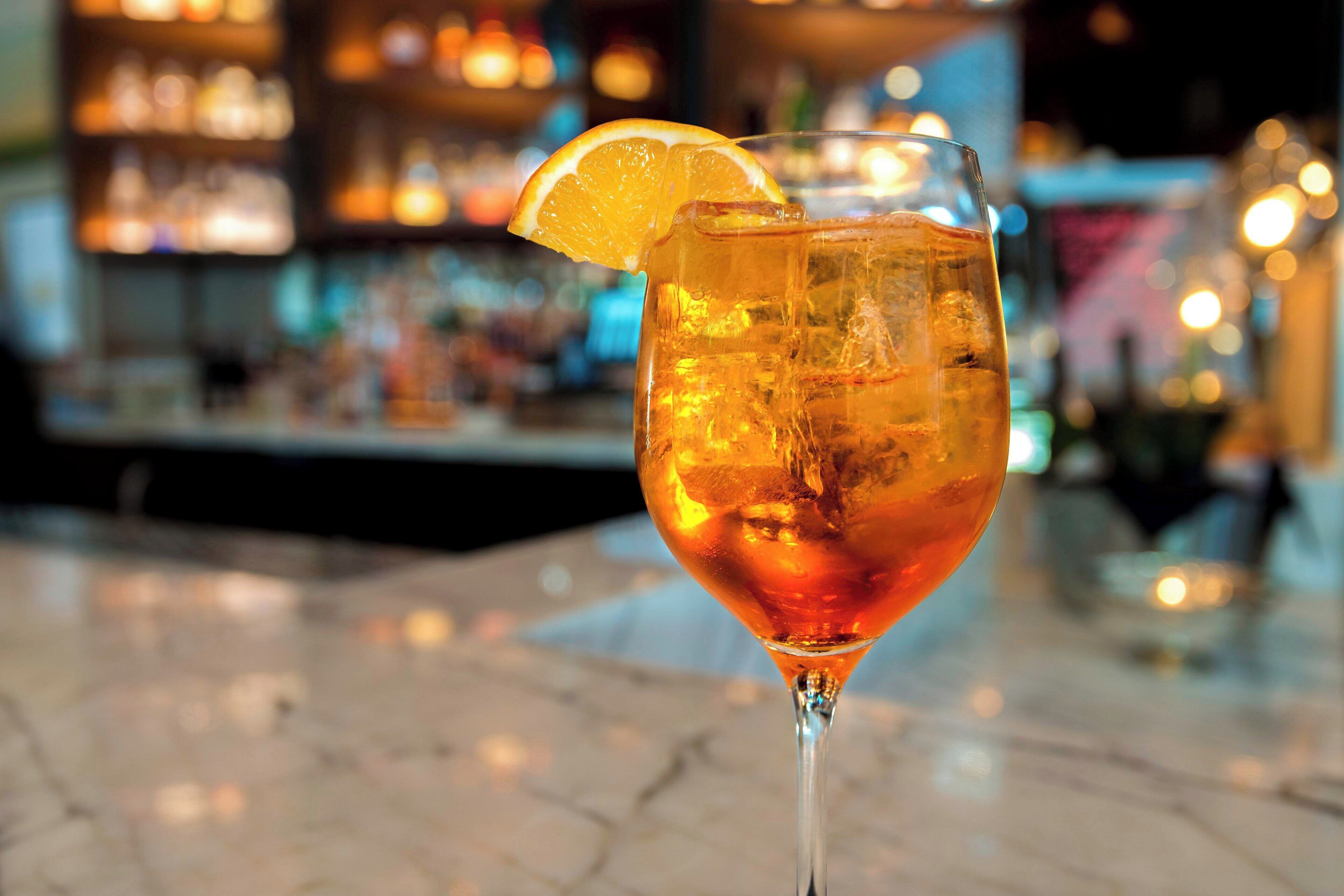 A cocktail glass with a lemon slice garnish on a bar counter.