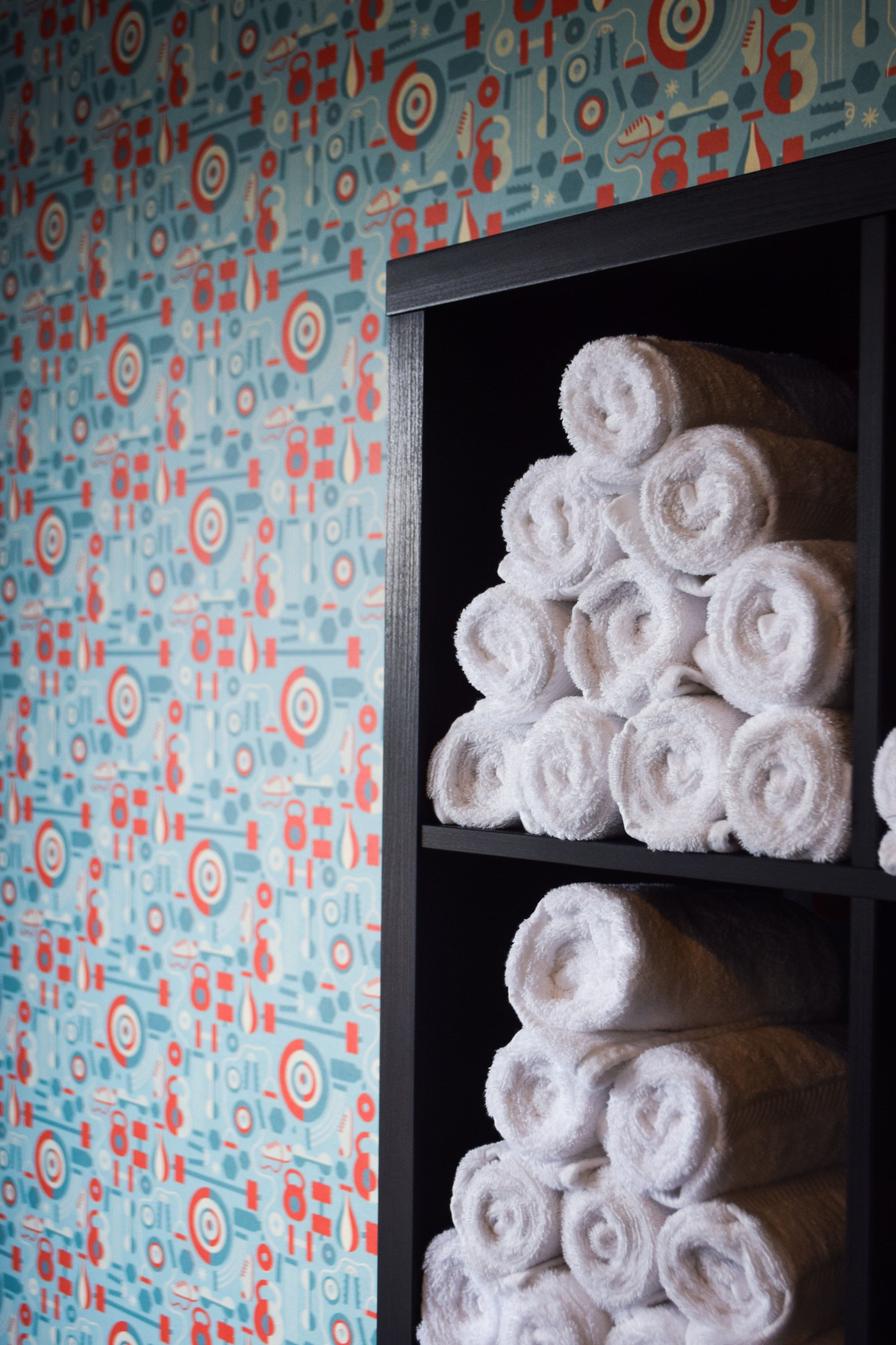 A wall with a geometric pattern and a shelf with neatly rolled towels.