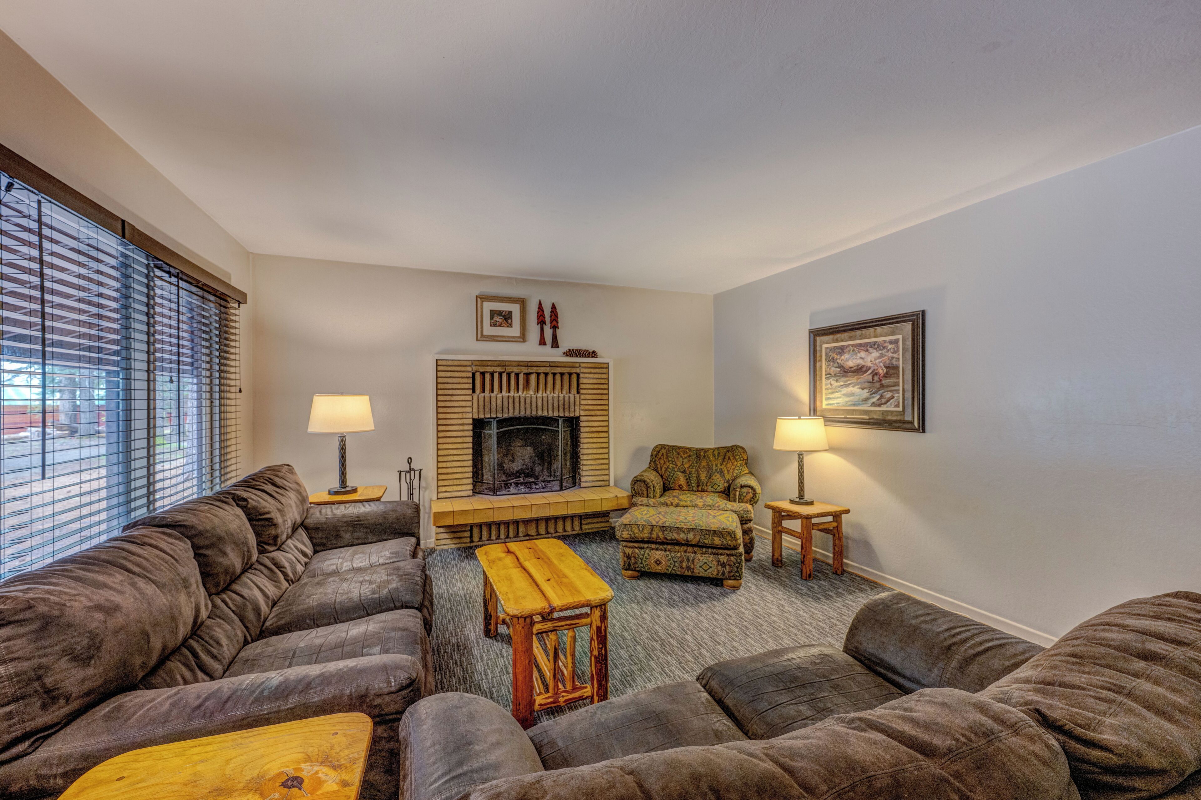 A living room with a fireplace, sofas, a coffee table, and lamps.