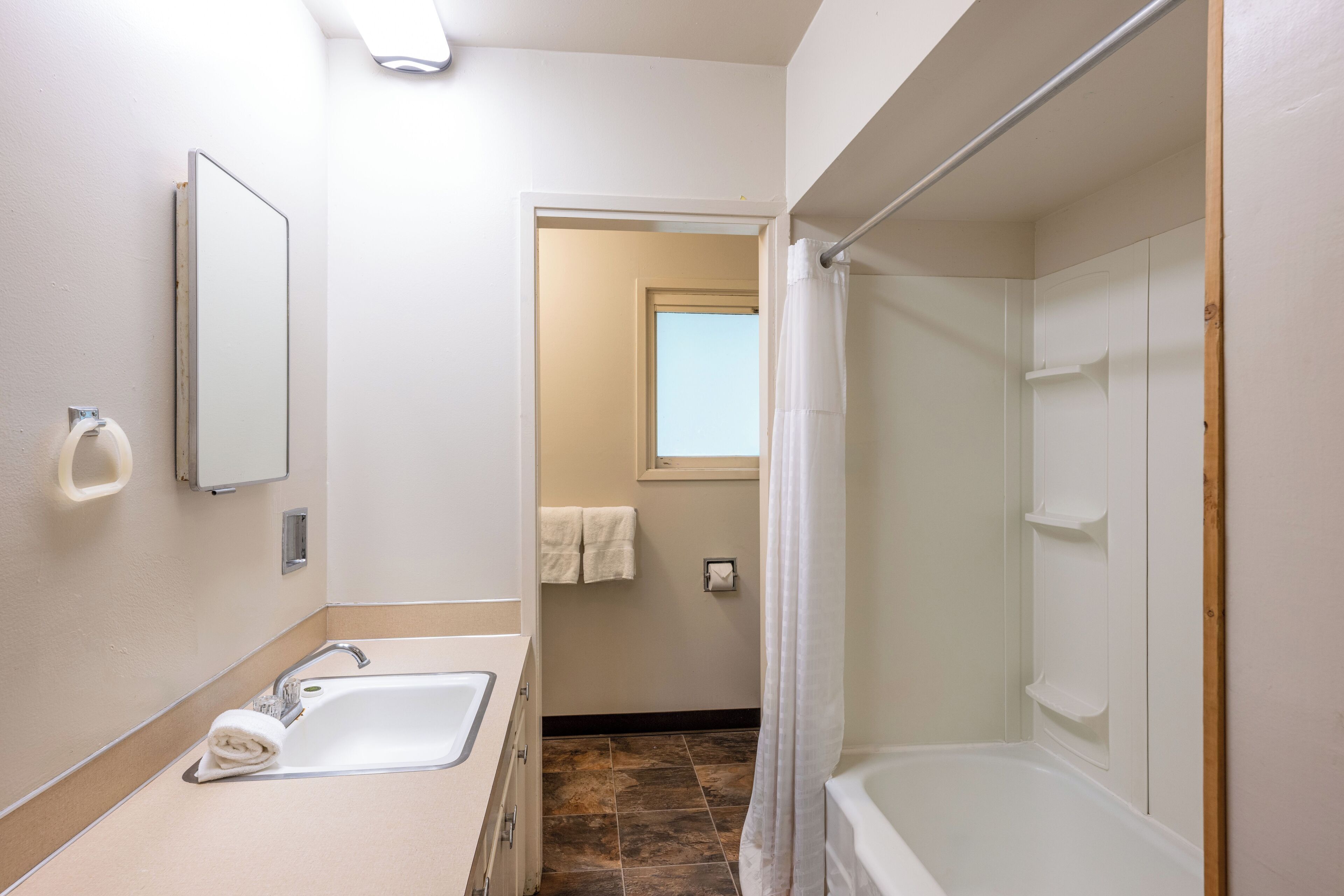 A bathroom with a sink, mirror, shower, and a towel rack.