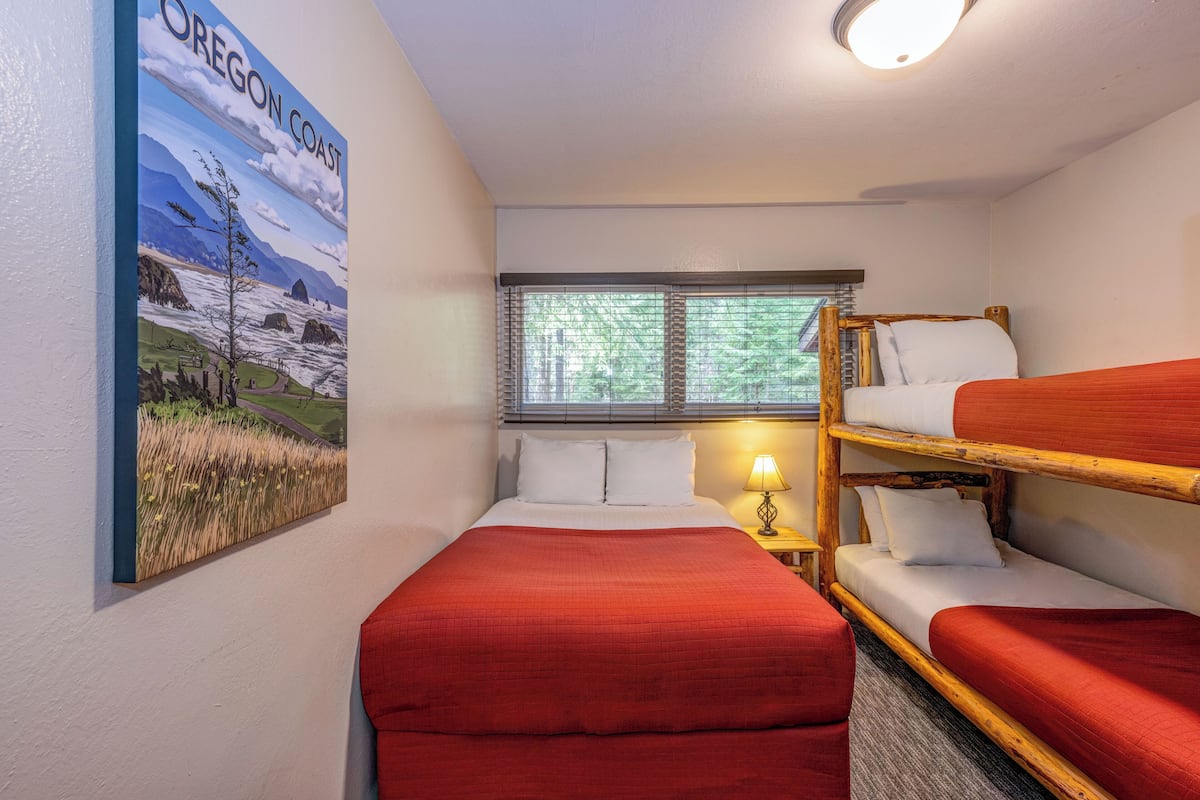 Quarto com cama, beliche, janela com persianas, luminária e pintura na parede da costa de Oregon.