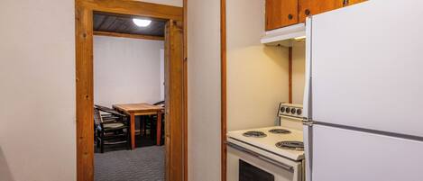 Una cocina compacta con armarios de madera, un refrigerador blanco y una estufa.