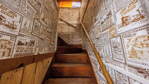 A staircase with wooden steps and handrails, surrounded by walls covered with vintage newspaper clippings. - Union Creek Resort (Prospect)