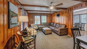 A wooden-paneled room with a sectional sofa, a dining table, and a ceiling fan. - Union Creek Resort (Prospect)