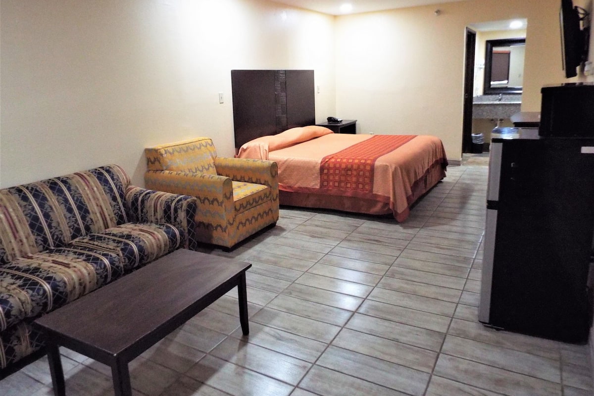 A hotel room with a sofa, armchair, bed, and a small table.