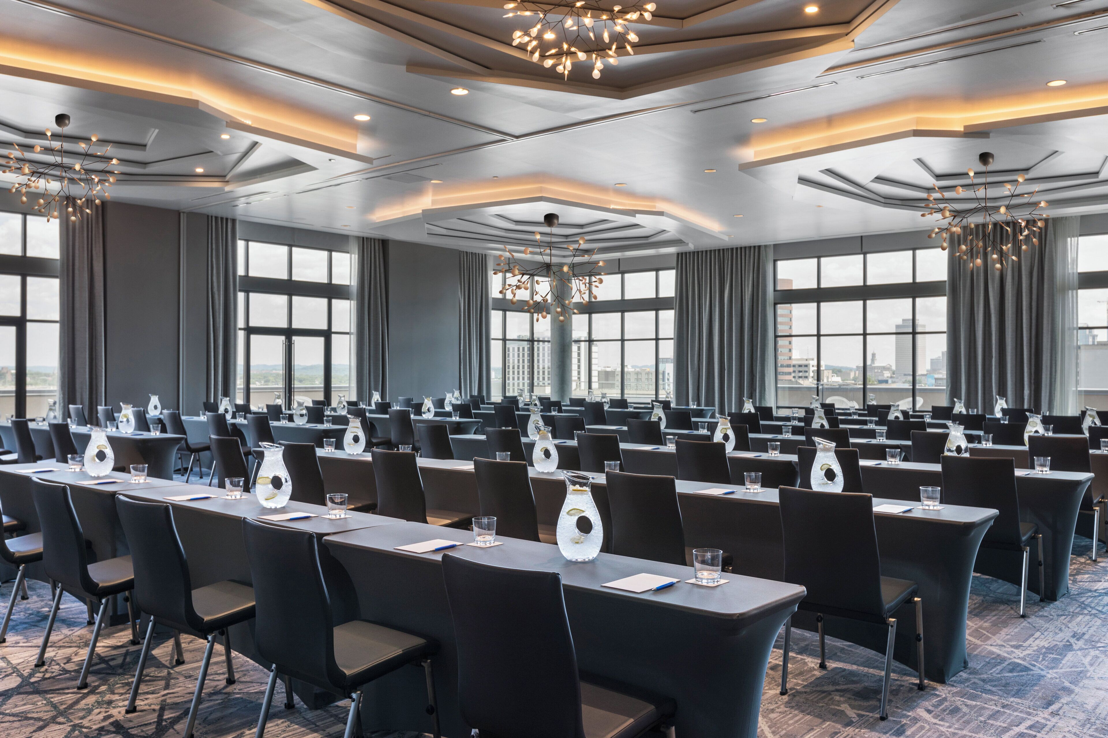 A conference room with tables, chairs, and a modern chandelier.