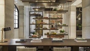 Un comedor moderno con una mesa larga, dos sillas y una estantería llena de libros y objetos decorativos.