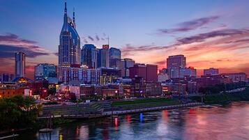 A city skyline at dusk with prominent skyscrapers and a river reflecting lights.