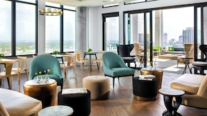 Amplia sala de estar con diversas opciones de asientos, ventanas grandes que ofrecen vistas a la ciudad y un diseño de interiores moderno.