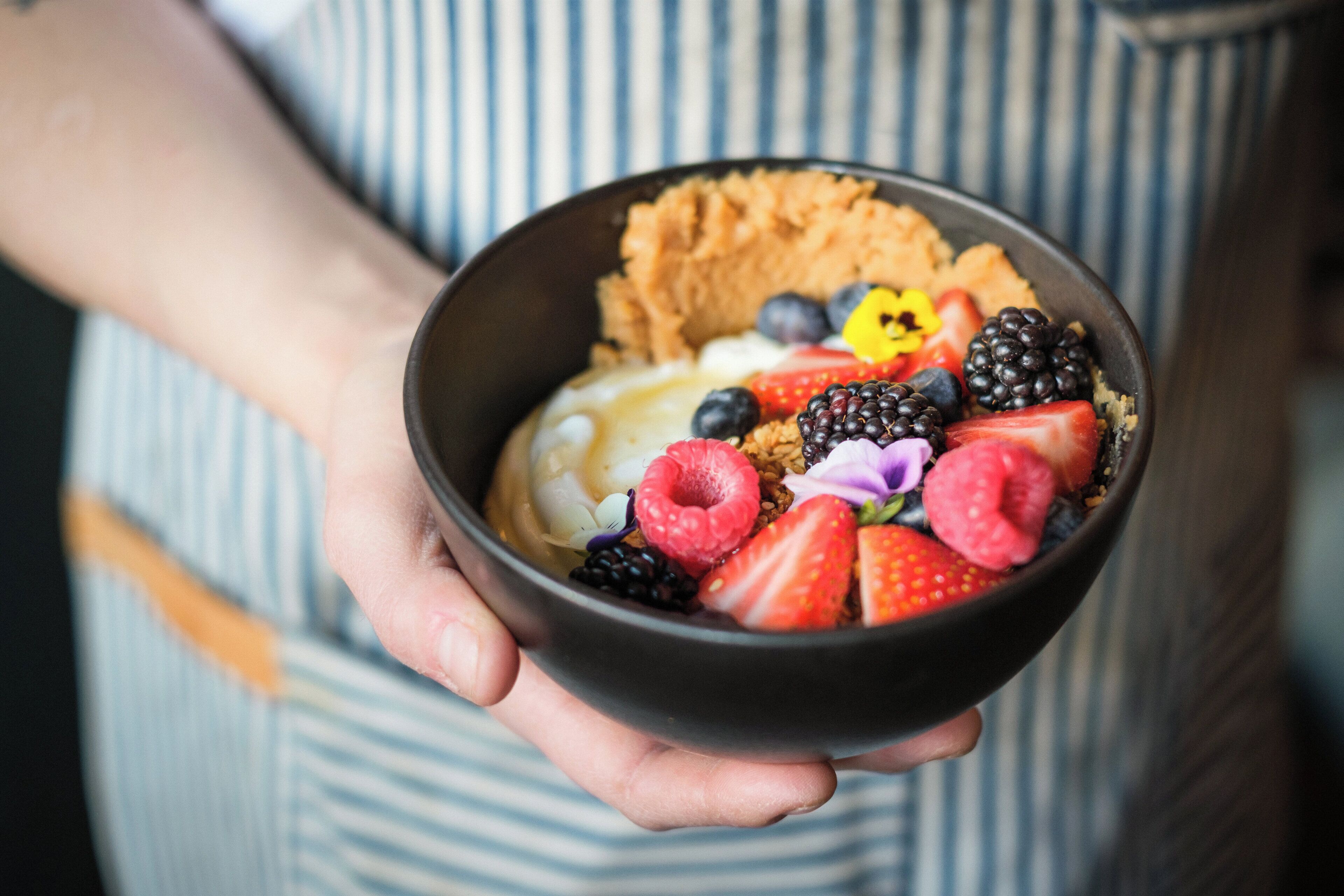 Eine Person hält eine Schüssel mit Obst und Joghurt-Parfait.