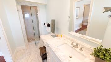 A bathroom with a large mirror, a sink, and a shower.