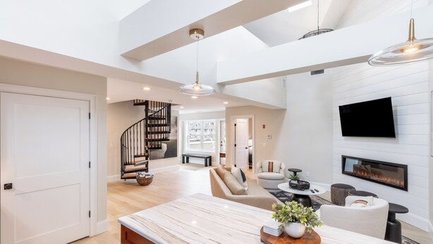 A spacious living area with a large marble island, a fireplace, and a modern staircase. - The Newport Lofts – 543 Thames Street (Newport)