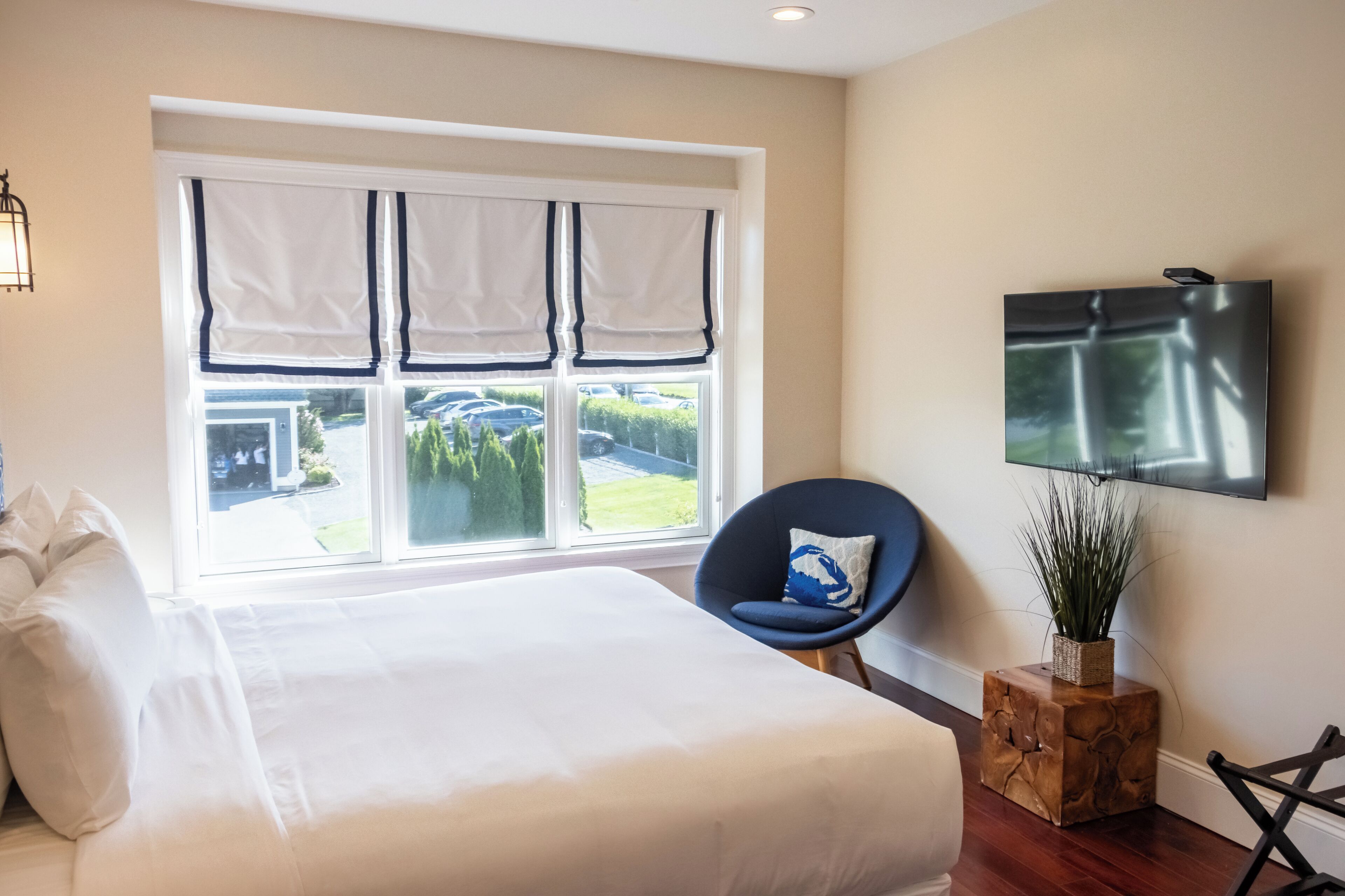 A bedroom with a large bed, a chair, a TV, and a window with curtains.