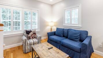 A living room with a blue sofa, a plaid armchair, a wooden coffee table, and a lamp.