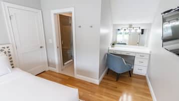 A bedroom with a bed, a desk, a chair, a mirror, and a wardrobe.