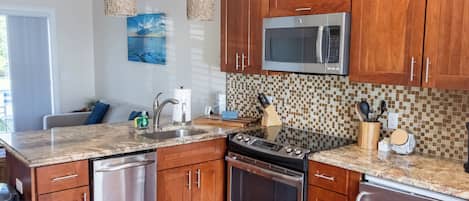 Cozinha moderna com armários de madeira, eletrodomésticos de aço inoxidável e painel de azulejos.