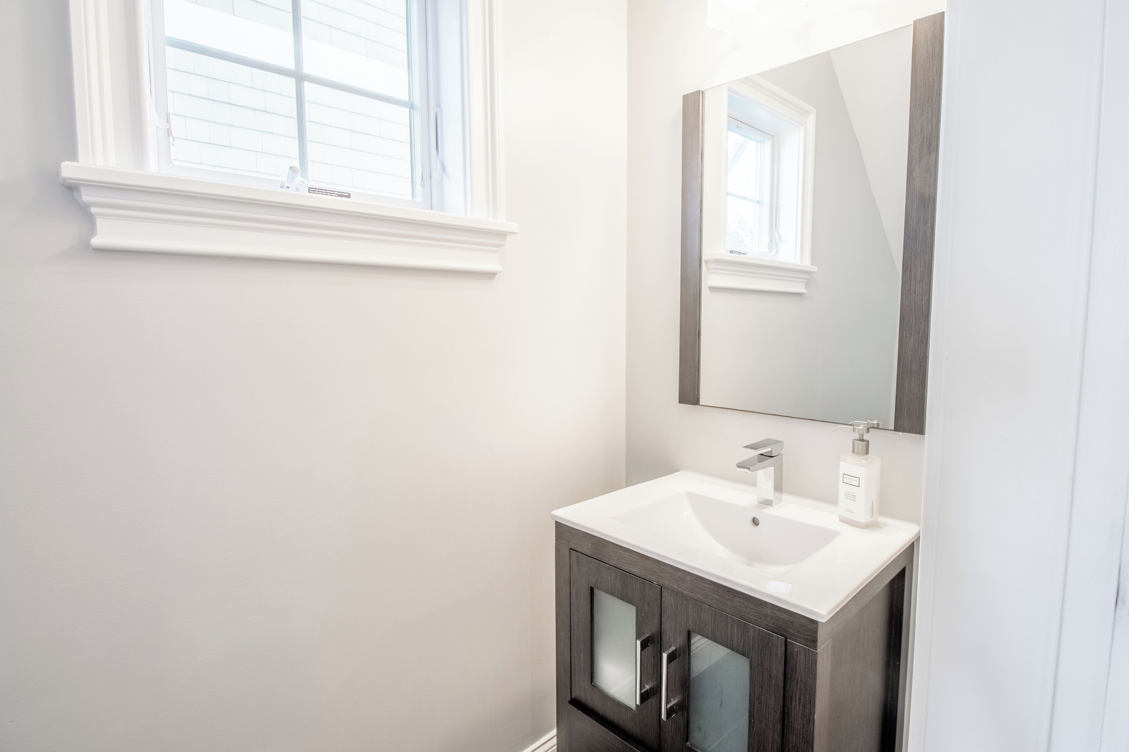 A bathroom with a white sink, dark cabinets, and a large mirror.