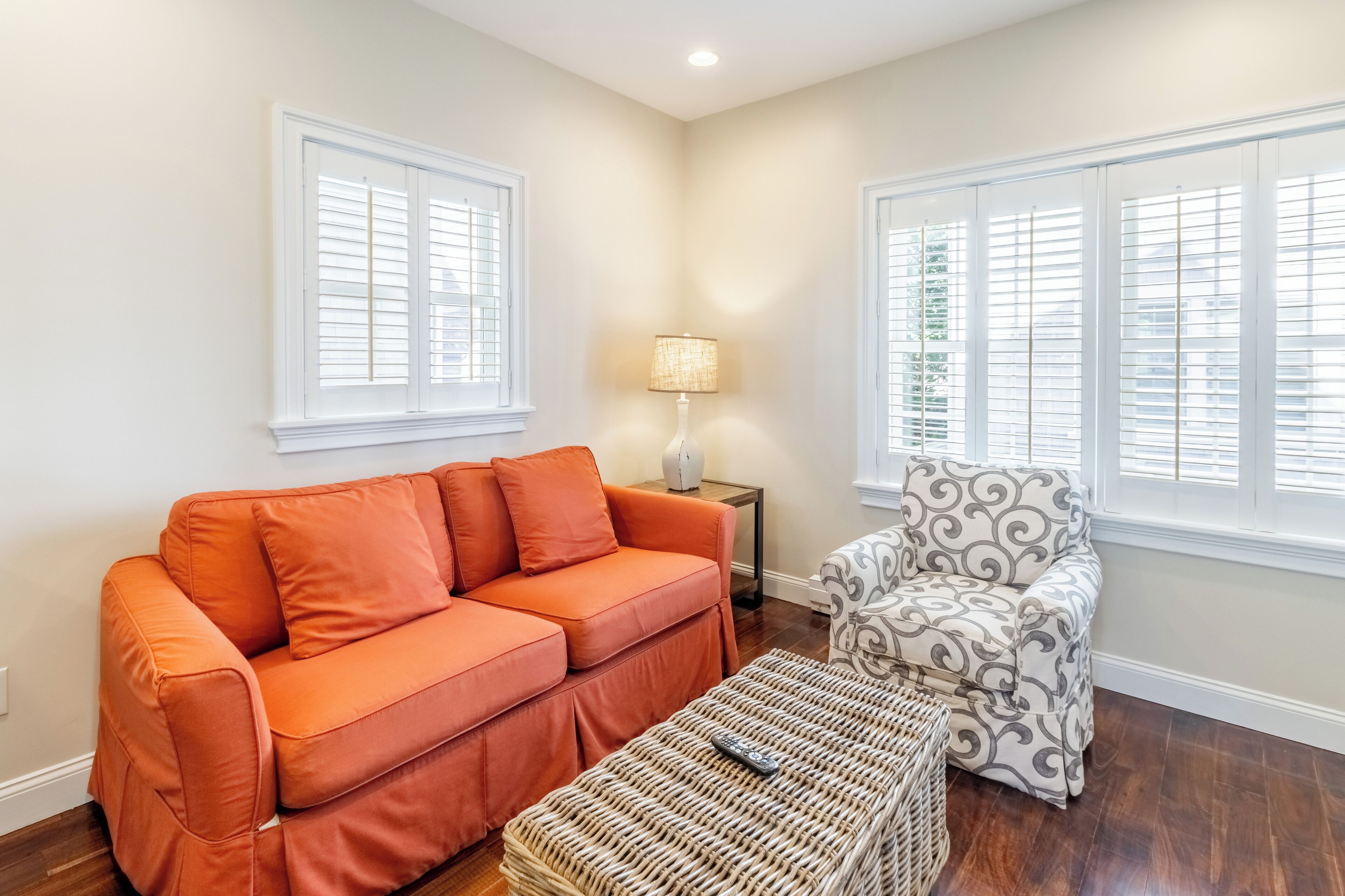 A living room with a sofa, ottoman, and patterned armchair.