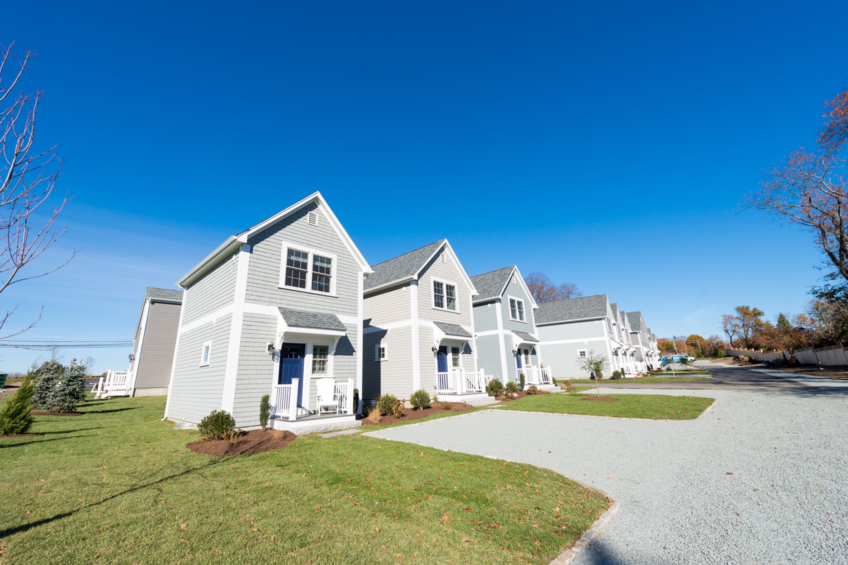 A row of modern two-story houses with a well-maintained lawn and driveway.