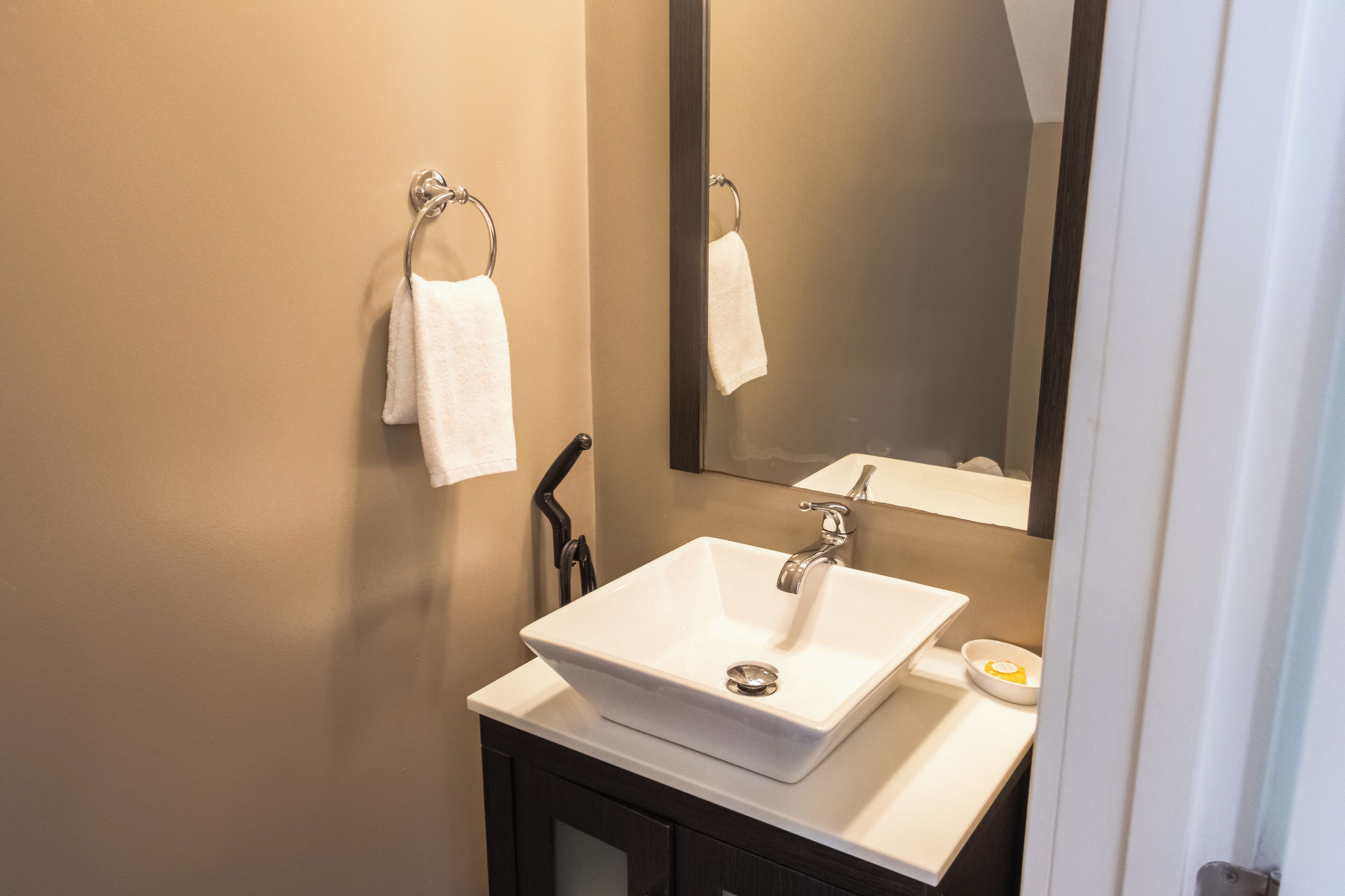 Een badkamer met een wit wastafelmeubel, een spiegel en een handdoekrek.