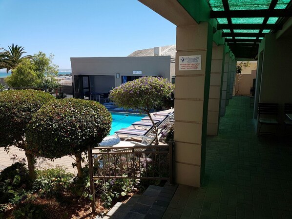 A pool area with lounge chairs, a sign indicating no children allowed, and a view of the ocean. - Seagulls Guest House (Langebaan)