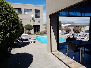 A pool area with lounge chairs and a view of a building with a satellite dish. - Seagulls Guest House (Langebaan)
