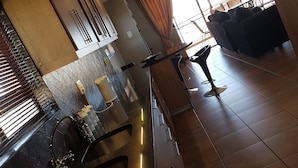 A modern kitchen with a built-in oven, a sink, and a dining area with a table and chairs.