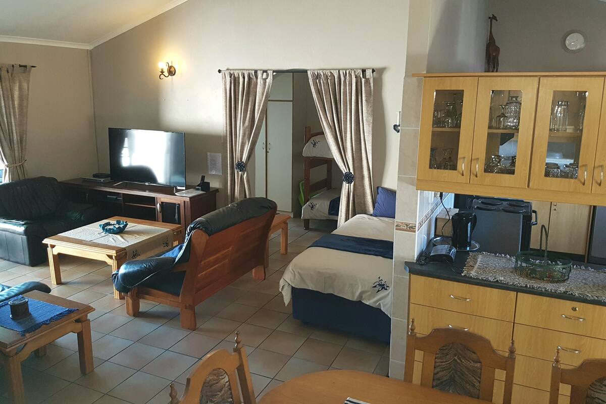 A living room with a television, sofa, and coffee table. There is a bedroom with a bed and a bathroom with a sink and mirror.