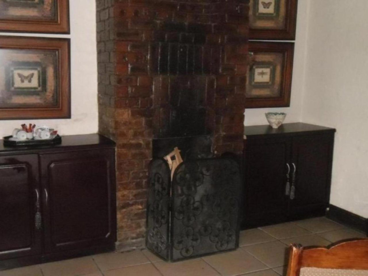Una stanza con camino in mattoni, mobili in legno scuro e pavimento piastrellato.