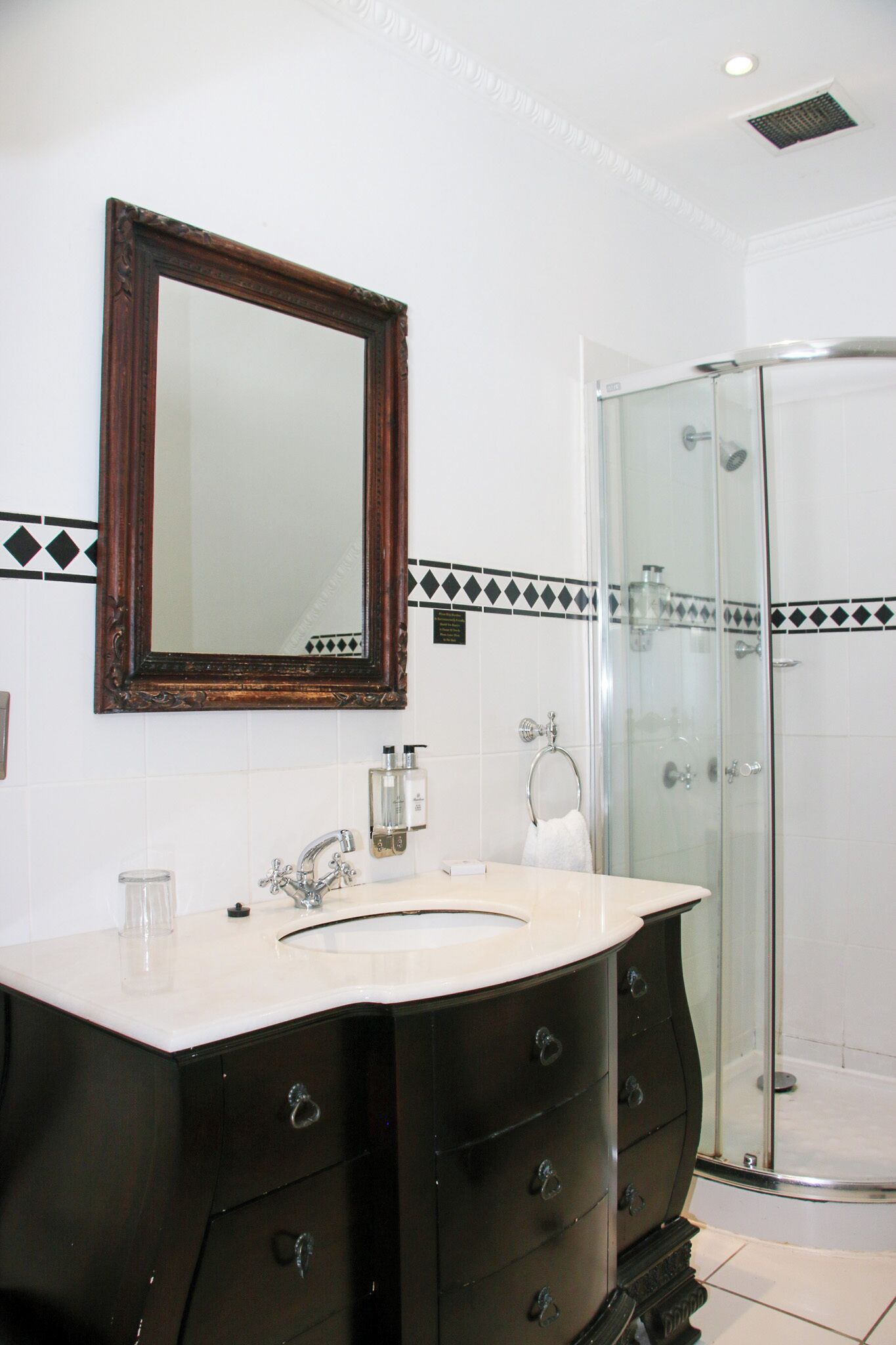 A bathroom with a large mirror, a sink with a vanity, and a glass shower enclosure.