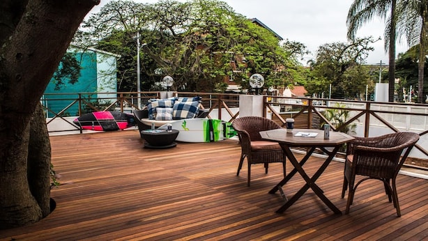 An outdoor deck with wooden flooring, wicker furniture, and a view of the surrounding area.