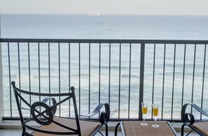 Enjoy the ocean view from this balcony with a table and two chairs.