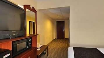 A hotel room with a bed, a television, a microwave, and a mirror.